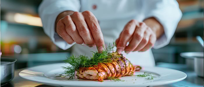 a chef carefully arranging garnishes on a plate, highlighting precision and attention to detail in food preparation