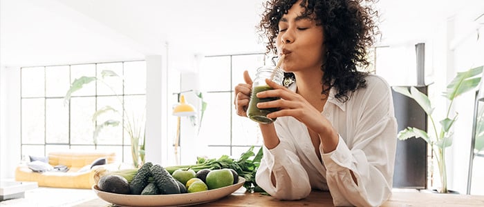 a woman enjoying a green juice, embodying the principles of clean eating and healthy living