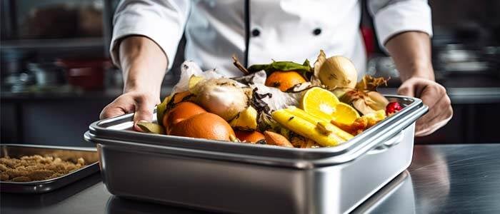a chef holds a container filled with leftover food, highlighting the issue of restaurant food waste